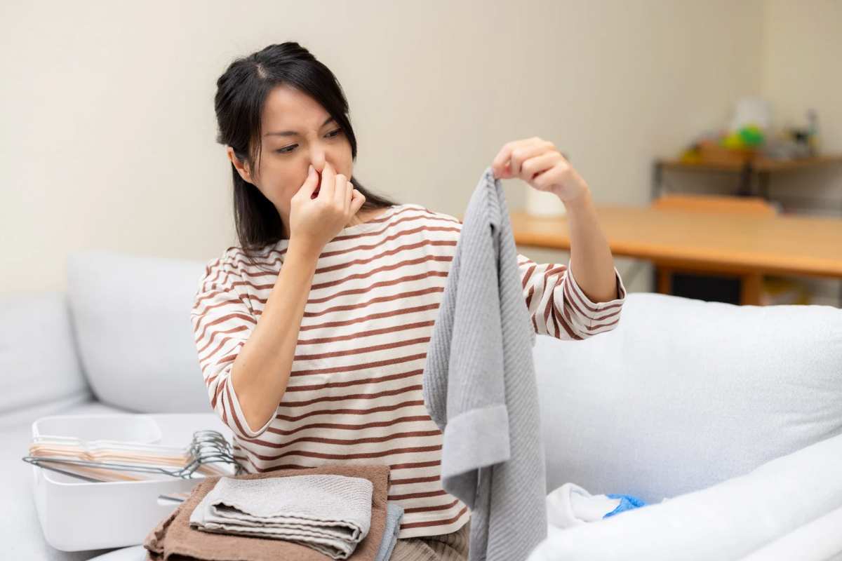 Donna che si chiude il naso e tiene in mano un capo di abbigliamento