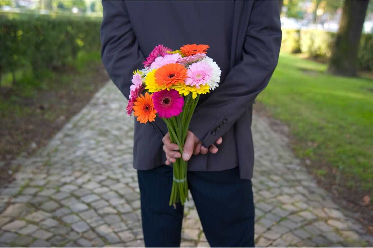 Uomo con mazzo fiori dietro la schiena